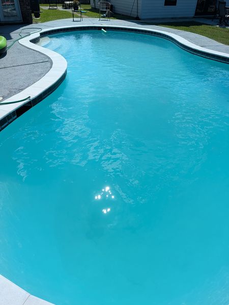 Kidney-shaped pool with bright turquoise water and light coping in the sun